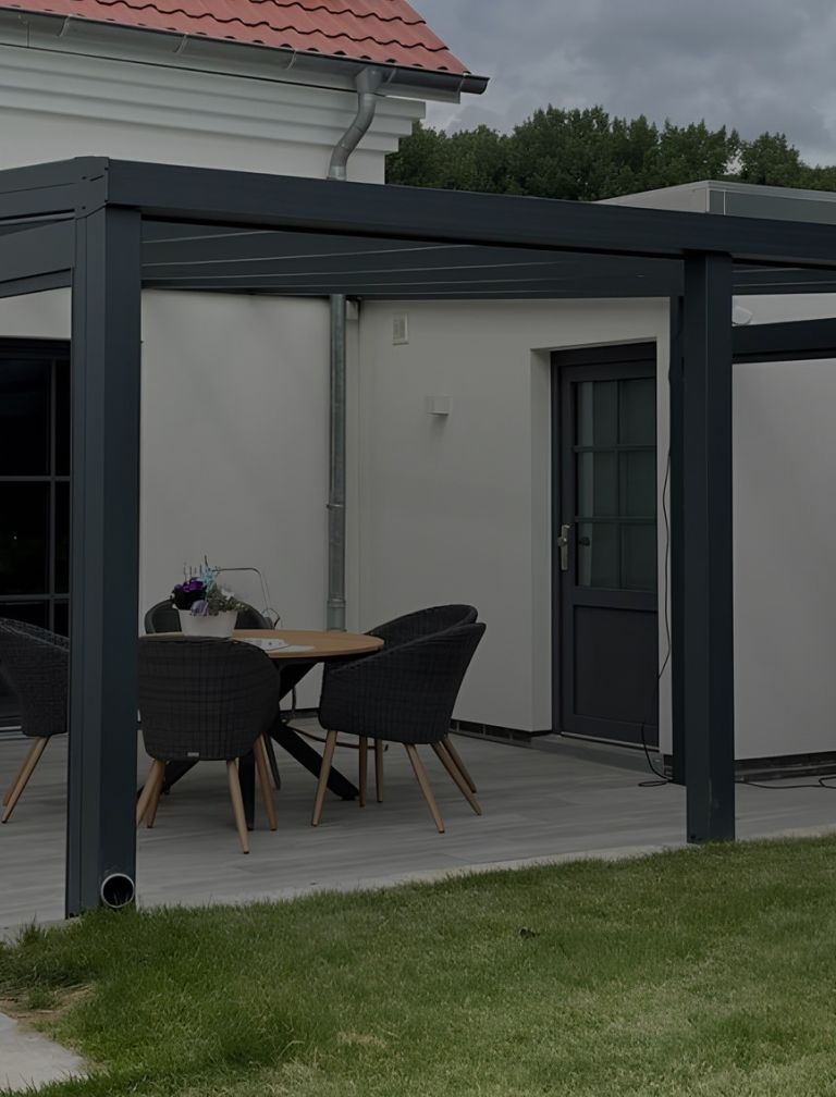 Gartenterrasse mit Tisch und Stühlen und dunkler Terrassenüberdachung