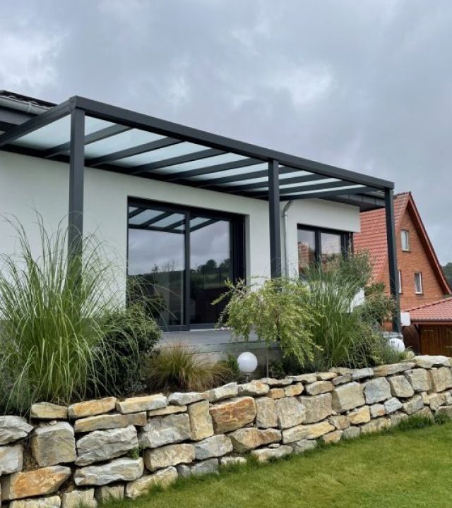 Ein stilvolles Haus mit einem transparenten Glasdach und einer robusten Steinwand, das zeitgenössische Architektur zeigt.